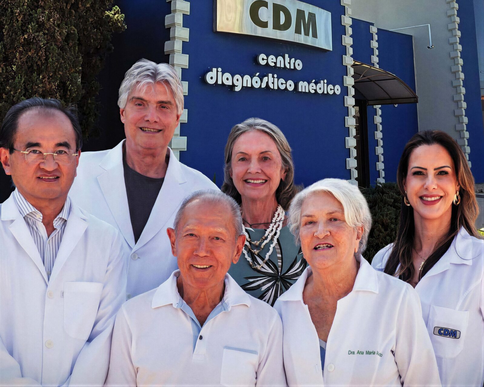 Médicos do CDM Dourados, de jaleco branco, em frente à fachada azul da clínica